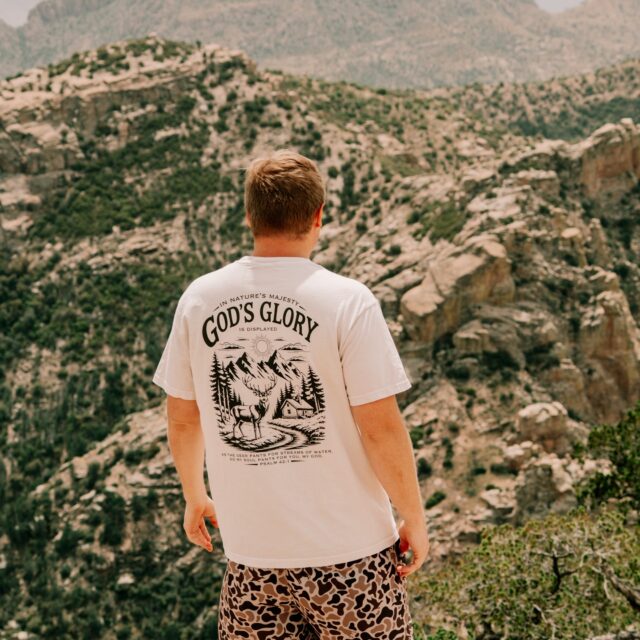 A God's Glory DTF print on a white tee, worn on a mountain overlook
